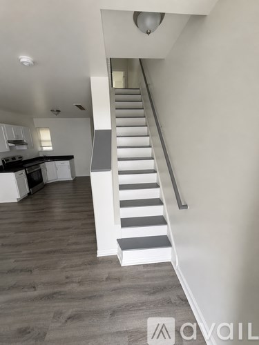 A staircase with black and white stripes leads up to a kitchen area.