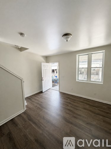 A room with wooden floors and a window with a view of a street.