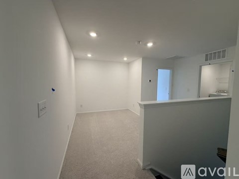 A spacious room with a carpeted floor and white walls.