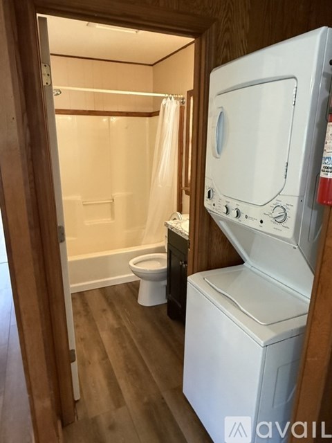 A small bathroom with a toilet, a washing machine, and a shower.