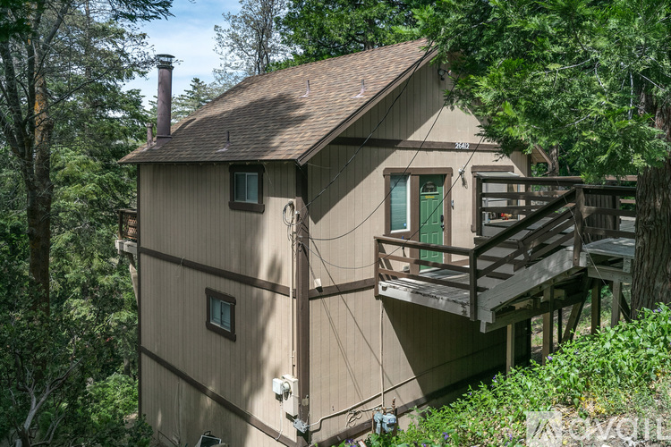 A house with a balcony is surrounded by trees.
