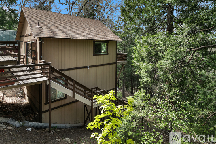 A house with a brown roof and a deck surrounded by trees.