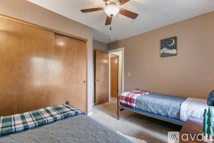 A bedroom with a bed, a ceiling fan, and a painting on the wall.