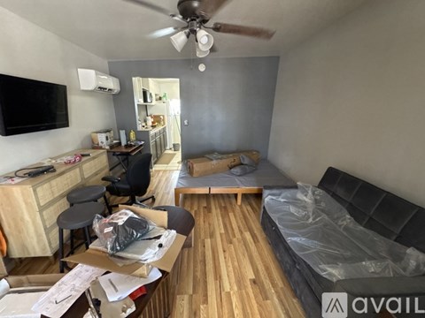 A room with a bed, a desk, and a ceiling fan.