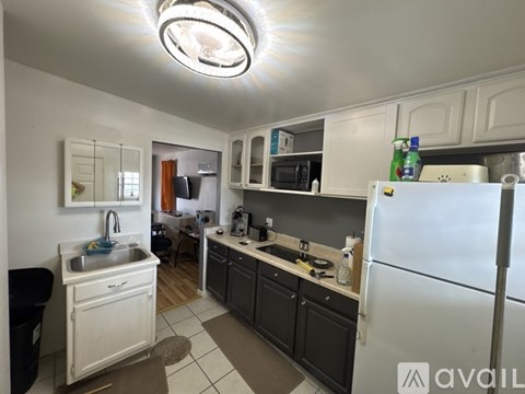 A kitchen with a white fridge, black cabinets, and a white sink.