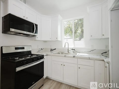 A kitchen with white cabinets and black appliances.
