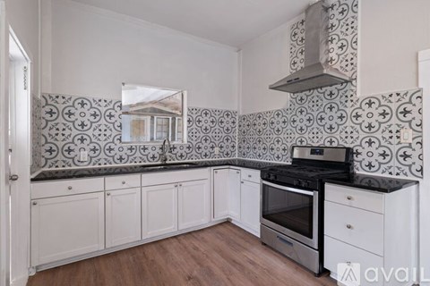 A kitchen with a black stove top oven and white cabinets.