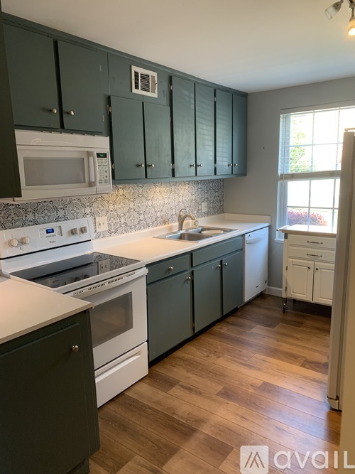 A kitchen with white appliances and green cabinets.