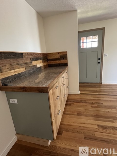 A kitchen with wooden floors and a stone counter top.