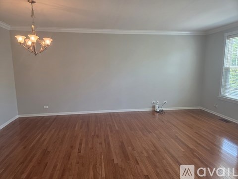 A room with wooden flooring and a chandelier.