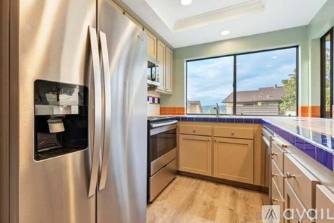 A modern kitchen with a stainless steel refrigerator and wooden cabinets.