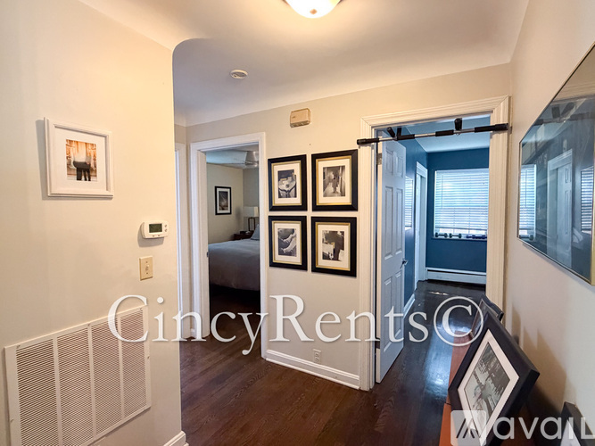 A hallway with a bedroom at the end and a mirror on the wall.