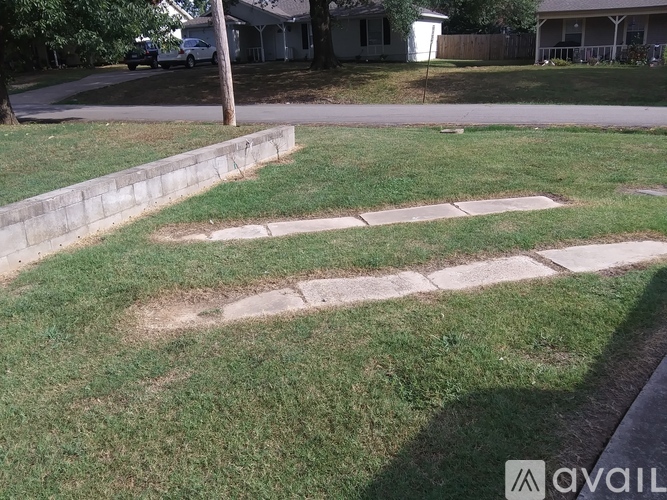 A grassy area with a concrete path and a white sign with the word "AVAIL" on it.
