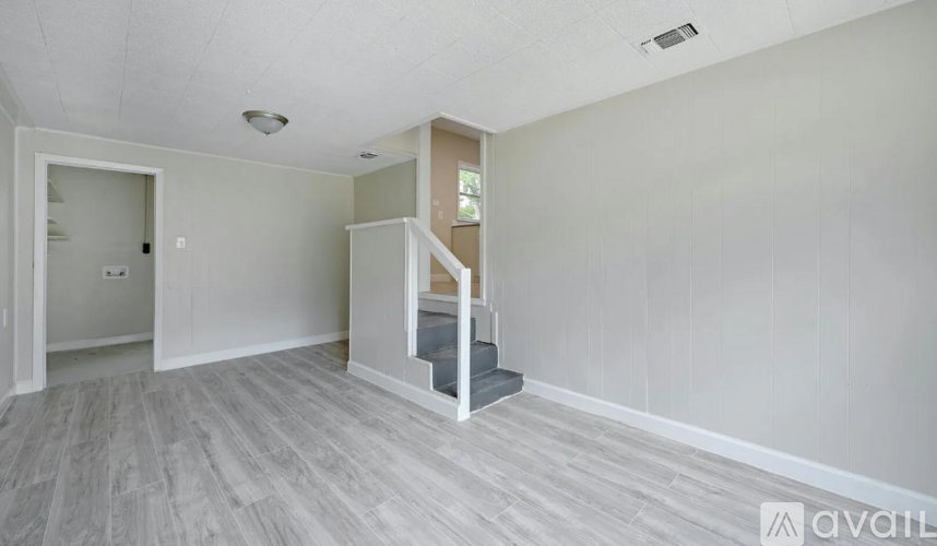 A spacious room with a staircase leading to a second floor.