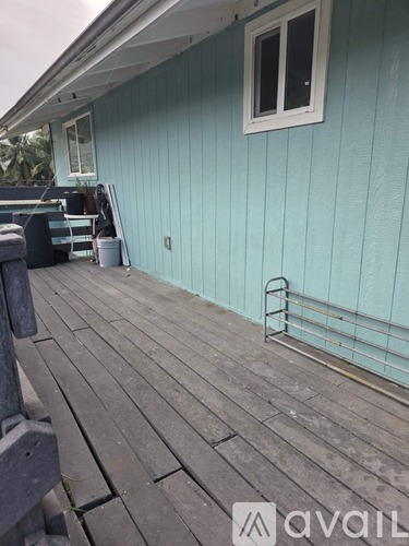 A wooden deck with a metal railing and a window on a blue house.