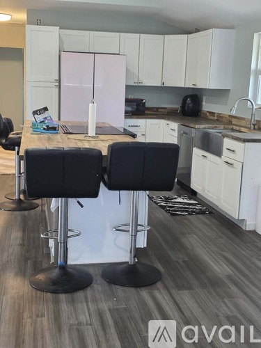 A kitchen with a table and three bar stools.