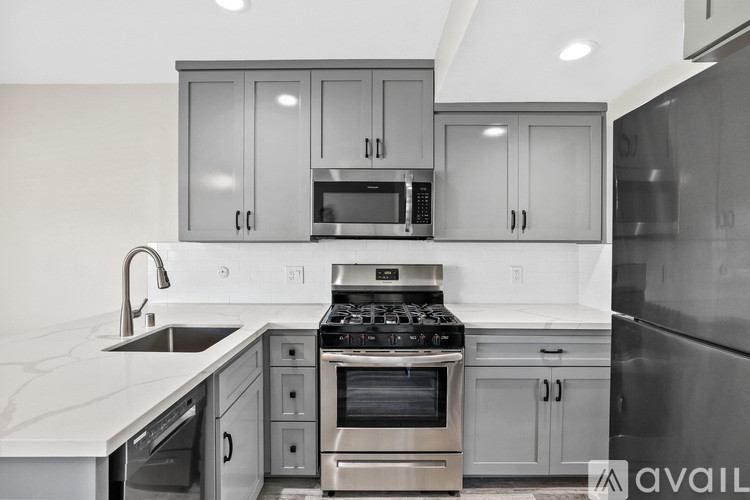 A modern kitchen with stainless steel appliances and grey cabinets.