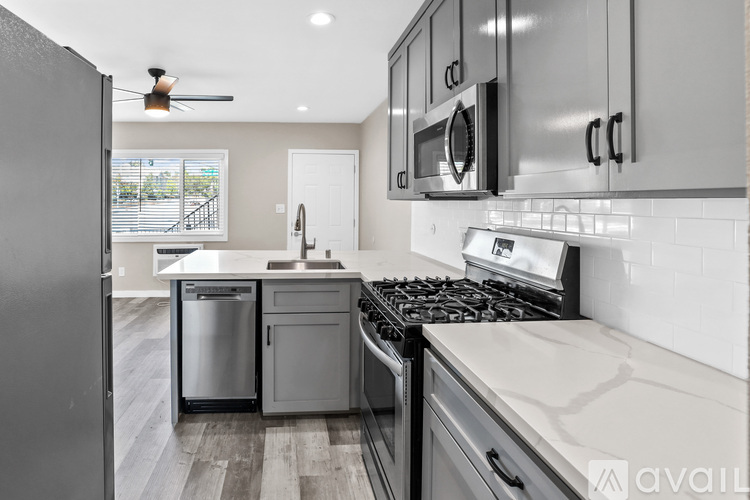 A modern kitchen with a stainless steel refrigerator and a black stove top.