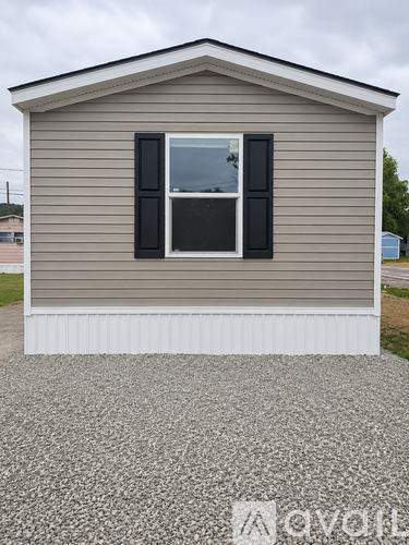 A small house with a grey siding and a white window trim.
