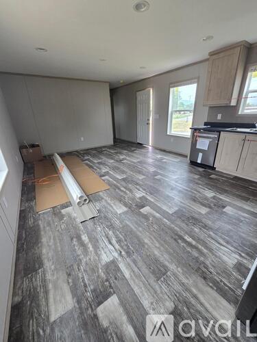 A room with wooden flooring and a wall on the left side.