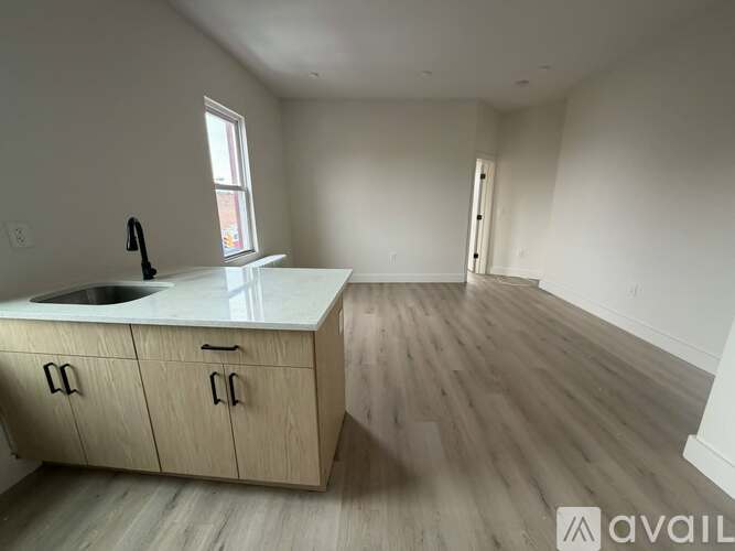 A kitchen with a sink, cabinets, and a window.
