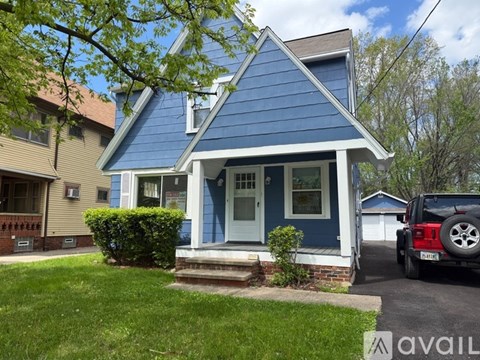 A blue house with a white door and a red vehicle parked in front.