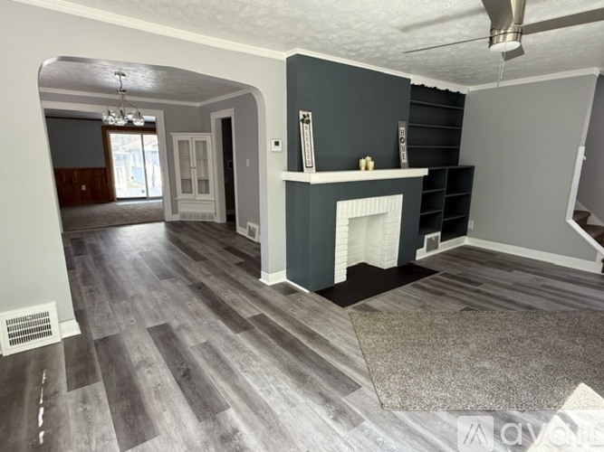 A living room with a fireplace and grey flooring.