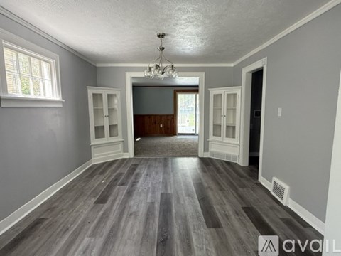 A spacious room with wood flooring and a chandelier.
