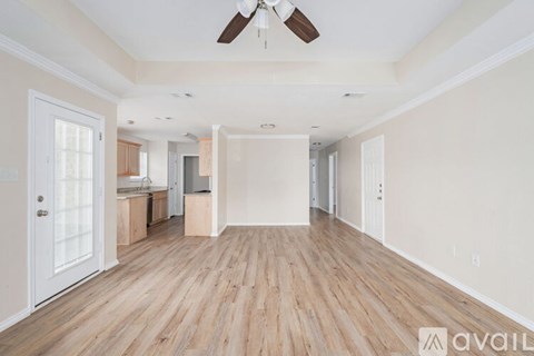 A spacious room with wooden flooring and a ceiling fan.