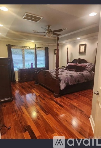 A bedroom with a large bed and wooden floors.