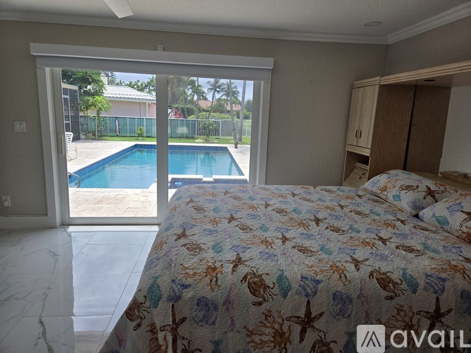 A bedroom with a large bed and a pool outside the window.