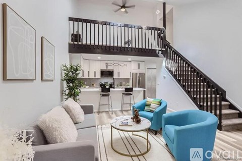 A living room with a grey couch, a coffee table, and a staircase.