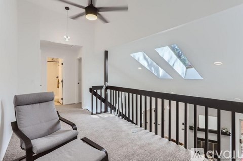 A living room with a grey chair and a ceiling fan.