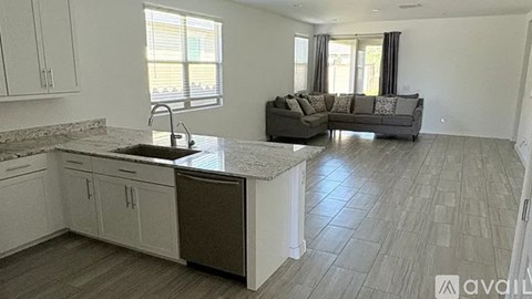 A kitchen with a sink and a couch in the living room.