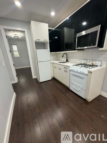A kitchen with white appliances and wooden floors.