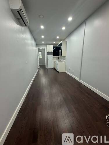 A long hallway with wood floors and white walls.