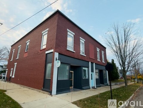 A red brick building with a black awning and a white sign on the front.