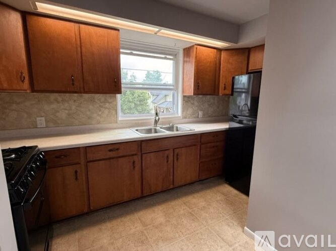 A kitchen with wooden cabinets and a black refrigerator.