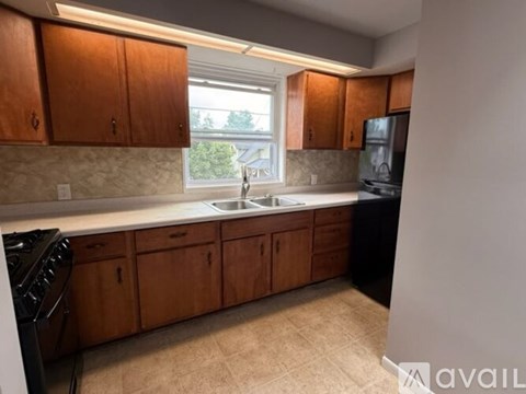 A kitchen with wooden cabinets and a black refrigerator.