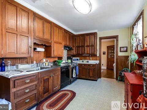 A kitchen with wooden cabinets and a red rug on the floor.