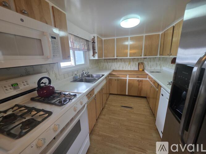 A kitchen with a white stove top and wooden cabinets.