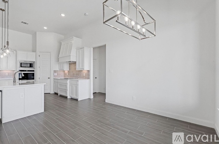 A modern kitchen with white cabinets and a grey floor.