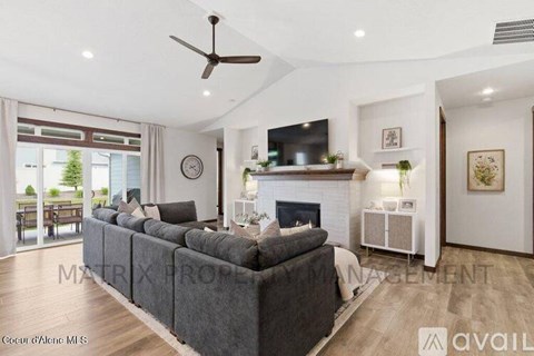 A living room with a grey couch and a fireplace.