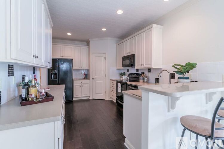 A kitchen with white cabinets and a black refrigerator.