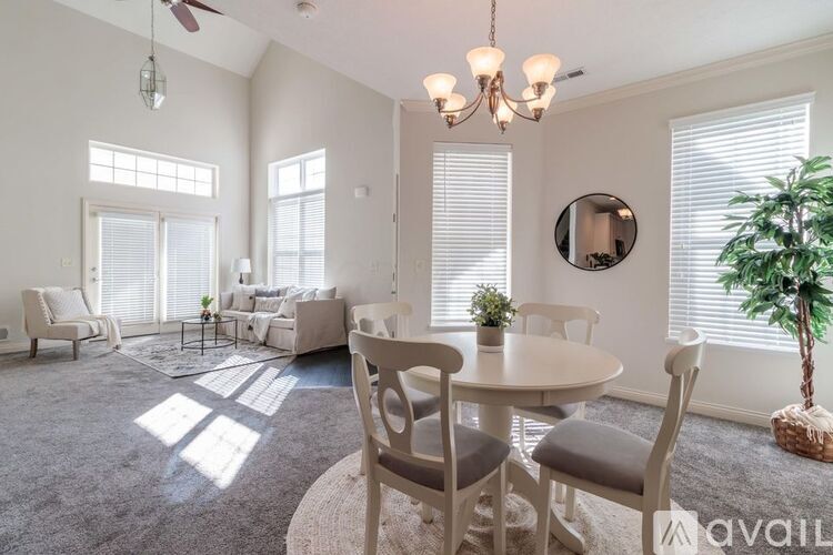 A living room with a dining table and chairs, a ceiling fan, and a potted plant.
