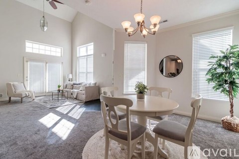 A living room with a dining table and chairs, a ceiling fan, and a potted plant.