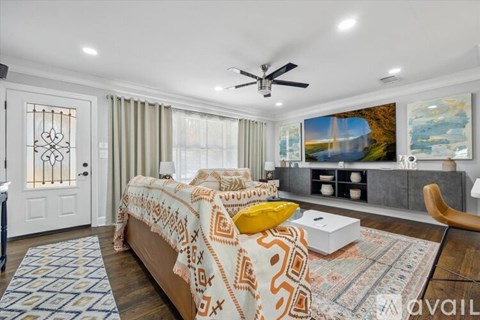 A bedroom with a bed, a ceiling fan, and a painting on the wall.