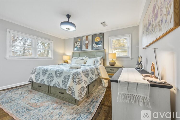 A bedroom with a patterned bedspread and a bed with a white and grey patterned blanket.