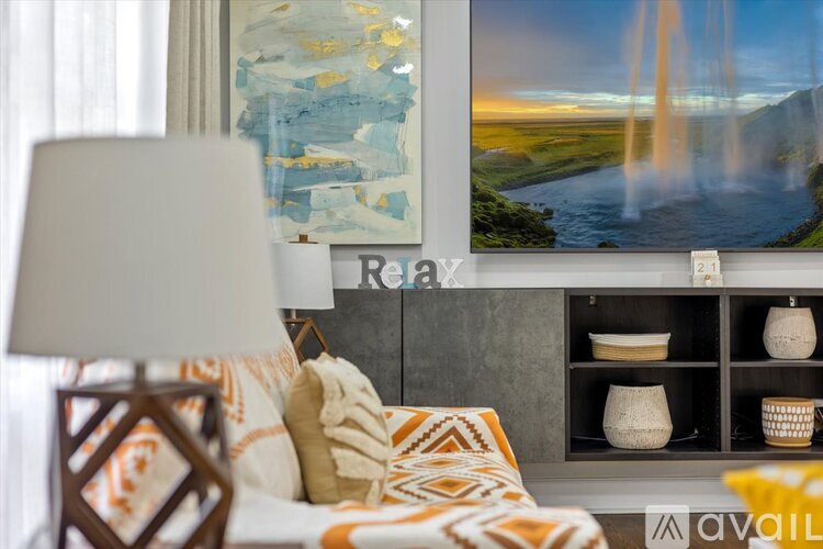 A living room with a large painting of a waterfall on the wall.
