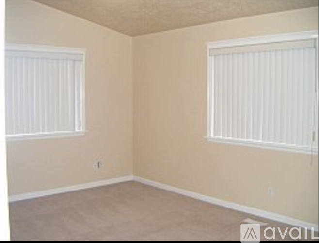 A room with two windows and beige walls.
